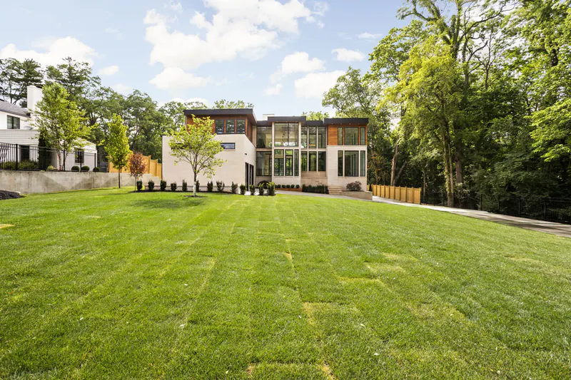 Contemporary custom home set back on a broad lawn surrounded by mature trees