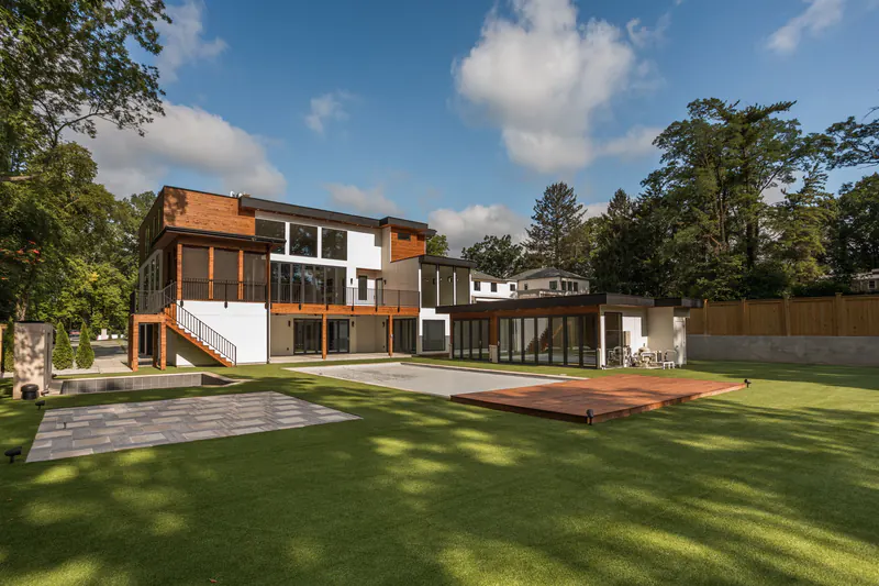 Backyard of a contemporary custom home with a screened upper porch, cedar cladding and outdoor terrace