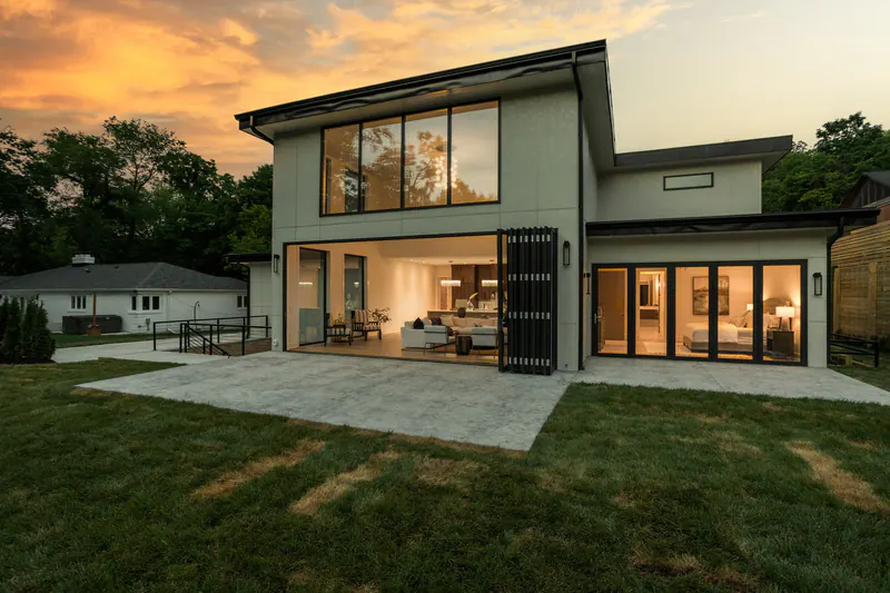 Folding glass wall opened to a covered patio on a modern custom home at dusk
