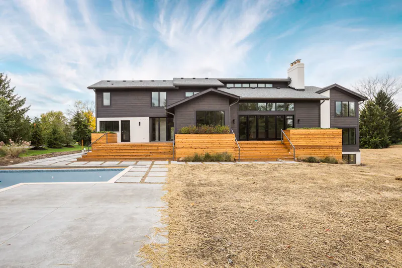 Rear of a two-tone modern home with cedar deck steps, built-in planters and a swimming pool