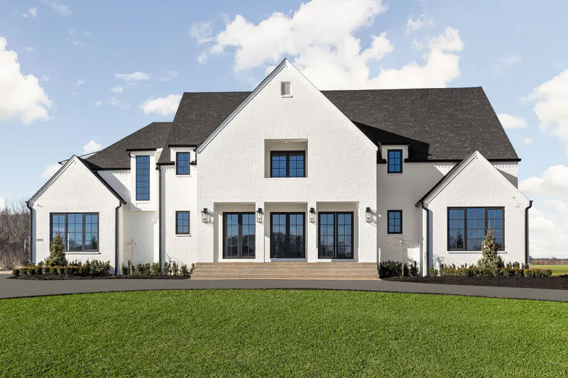 White painted-brick custom home with steep black roofs and black-framed windows